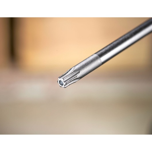 Close-up of a metal precision screwdriver bit with a star tip, shown against a blurred background.