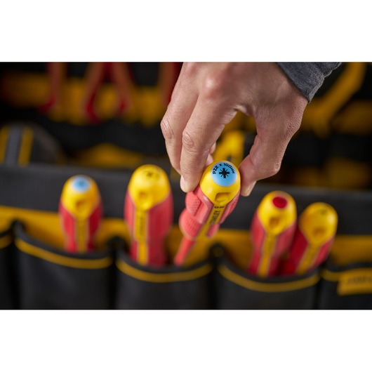 Hand selects an insulated screwdriver from a tool bag with other screwdrivers. STANLEY branding visible.