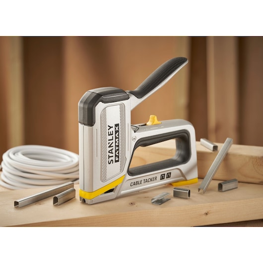 STANLEY FMHT70100-0 cable tacker tool on wood surface with cable staples and wire shown.