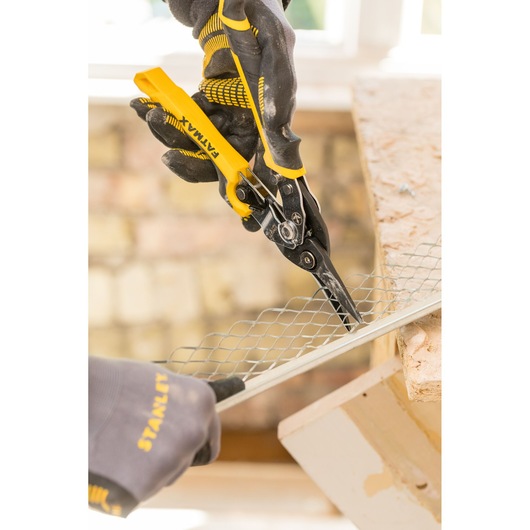 STANLEY FMHT73756-0 aviation snips cutting metal mesh, close-up, with gloved hands in a workshop.