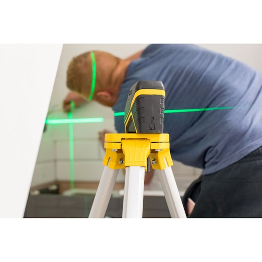 Photo of STANLEY FMHT77595-1 laser level on tripod projecting green lines in interior workspace.