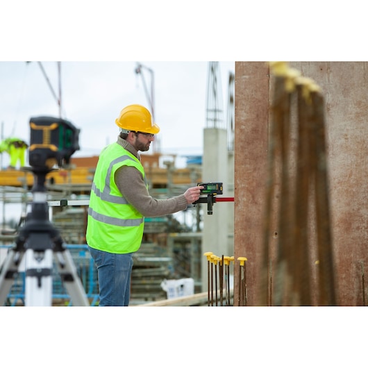 STANLEY FMHT77653-0 laser level used on tripod by worker at construction site.