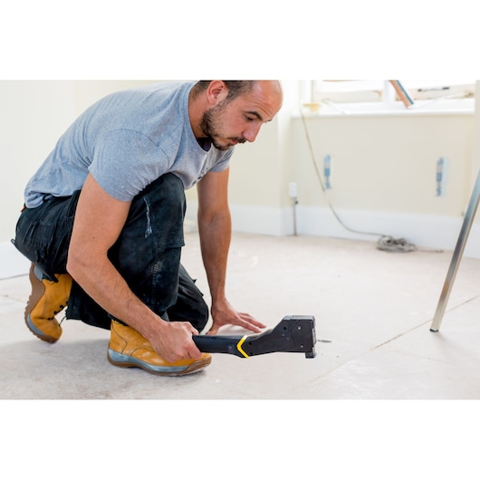 STANLEY FMHT81394-9 staple gun used by worker in construction setting, side angle photography.