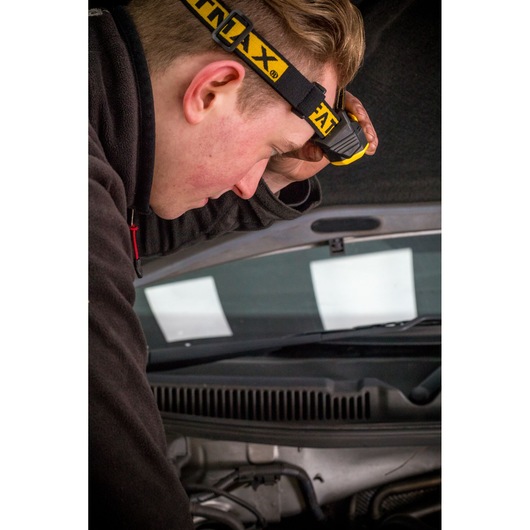 STANLEY FMHT81509-0 headlamp used by mechanic working under car hood, close-up photography.