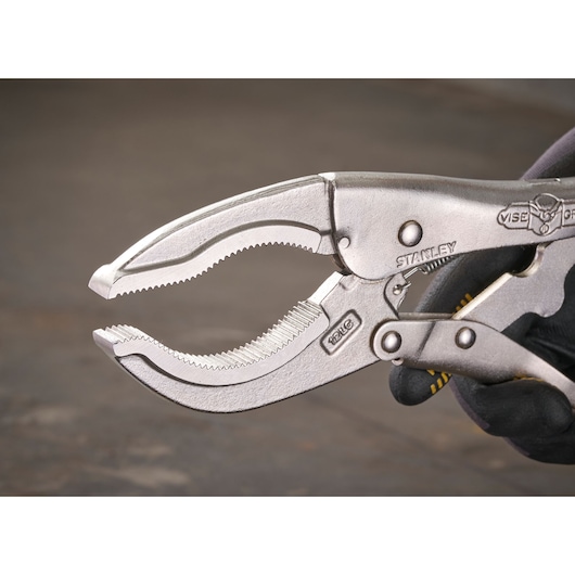 Close-up of a STANLEY locking pliers, showing serrated jaws and handle held by a gloved hand.