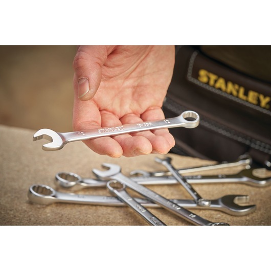 Photo of STANLEY FMMT13039-0 combination wrench in hand, with several wrenches on a work surface.