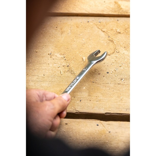 Photo of STANLEY FMMT13039-0 wrench held in hand on wooden surface, open-end design visible.