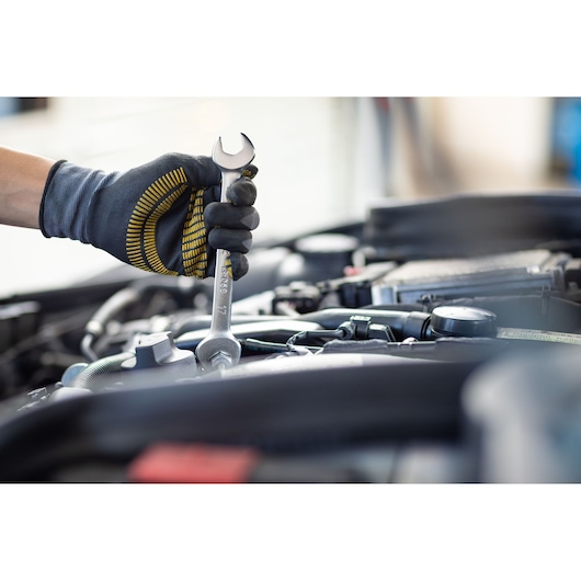 Photo of STANLEY FMMT13071-0 wrench held by gloved hand working on car engine, close-up view.