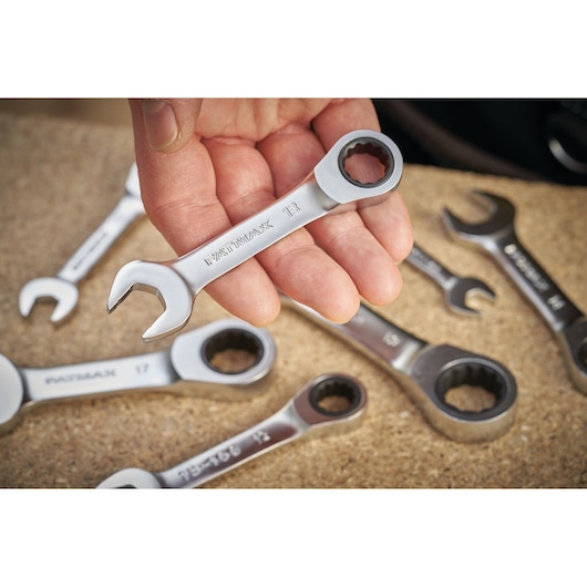 STANLEY FMMT13111-0 ratcheting combination wrench set, close-up of one wrench held in hand, others on work surface.