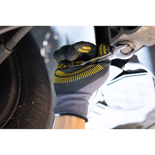 Photo of STANLEY FMMT13112-0 wrench in use, gloved hand tightening bolt near car tire.