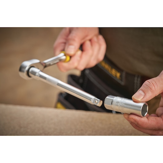 Photo of STANLEY FMMT17226-0 ratchet wrench and socket in use, held by a person wearing a tool belt.