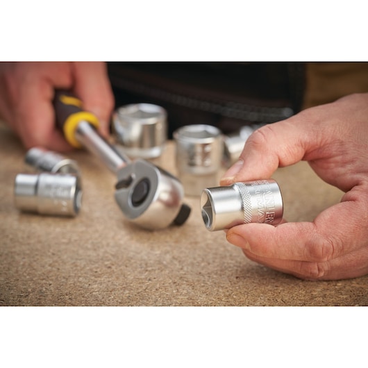 STANLEY FMMT17235-0 socket held in hand with ratchet and other sockets on wooden surface.