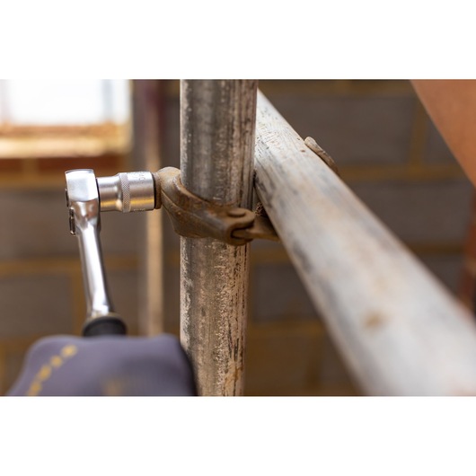 STANLEY FMMT17238-0 ratchet wrench tightening a scaffold clamp on metal pipes, close-up indoor.