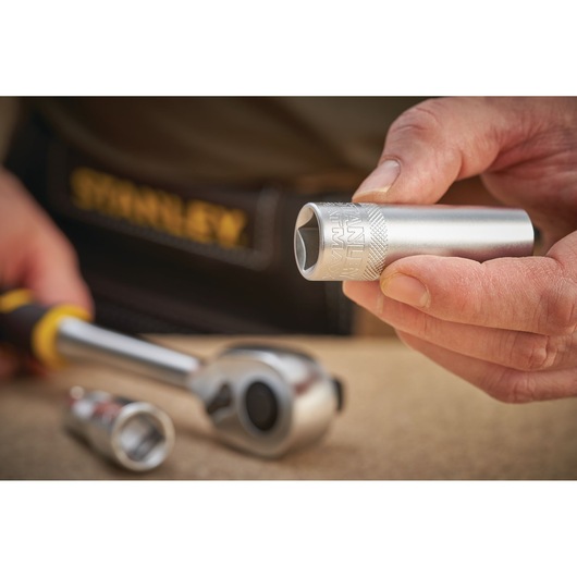 Photo of STANLEY FMMT17968-0 socket in hand, with ratchet and other sockets on workbench.