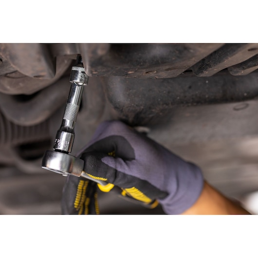 Photo of STANLEY FMMT25122-0 ratchet wrench being used under a car, gloved hand turning tool.