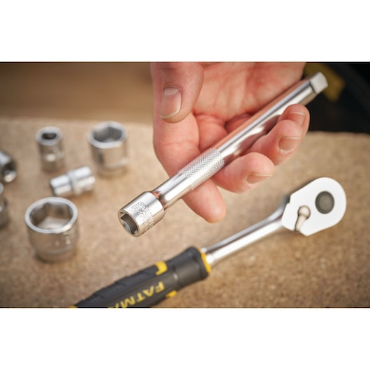 STANLEY FMMT25131-0 socket extension bar held by hand, with chrome sockets and ratchet on workbench.