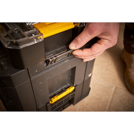 STANLEY FMMT98106-1 black toolbox with yellow latches, close-up of hand operating locking mechanism.