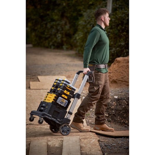 STANLEY FMMT98106-1 tool storage trolley with stacked boxes pulled outdoors by a person.