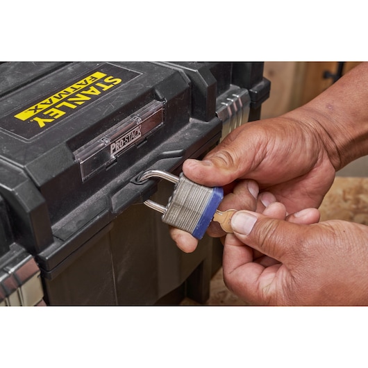 STANLEY FMST1-71971 toolbox secured with padlock, key held in hand, close-up photography.