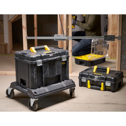 STANLEY FMST1-71972 black and yellow rolling toolbox with handle, shown in a construction area.
