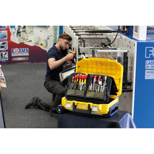 STANLEY FMST1-72383 tool case open, displaying assorted hand tools, yellow and black, in workshop setting.