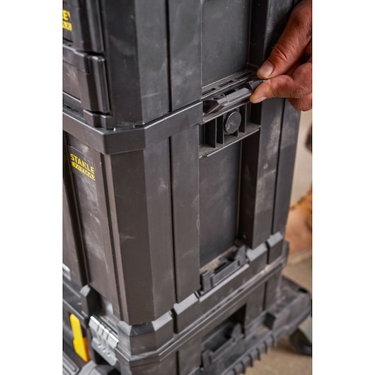 STANLEY FMST1-75794 black stackable tool box, side view, hand using locking latch.