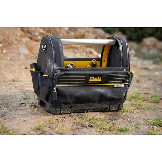 STANLEY FMST17626-1 tool bag with open top, black and yellow design, metal handle, outdoor ground view.