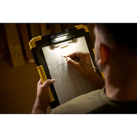 STANLEY FMST82721-1 clipboard with built-in LED light in use, holding architectural drawing, angled hand-held view.