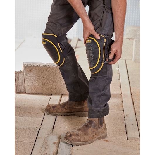 STANLEY FMST82961-1 knee pads with black and yellow design worn by worker on construction site.