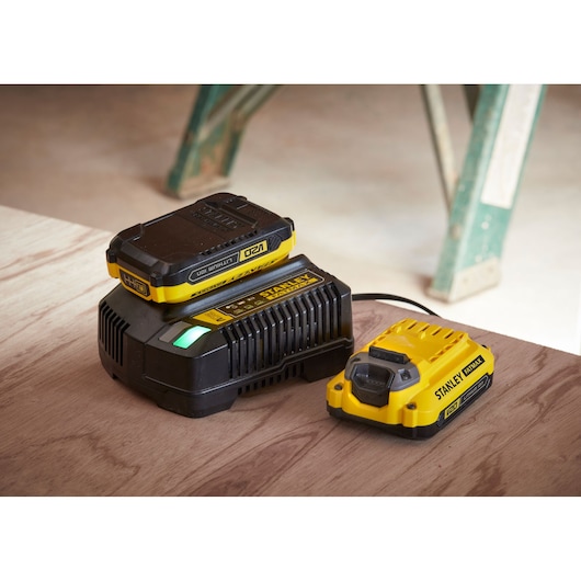STANLEY SFMCB14 battery charger and battery, yellow and black, side angle on wooden surface.