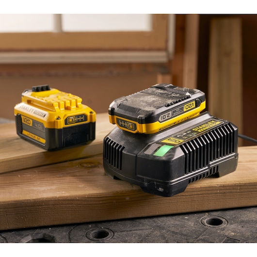 Photo of STANLEY SFMCB14 V20 lithium-ion battery and charger on wood, workshop background.