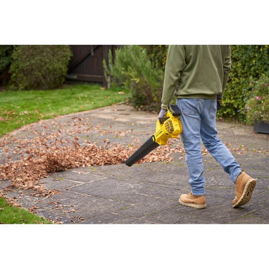 STANLEY SFMCBL714M1 leaf blower in use clearing leaves on patio, outdoor setting, side angle.