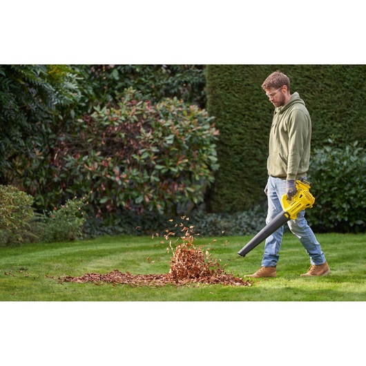 STANLEY SFMCBL714M1 leaf blower in use outdoors, blowing leaves on a green lawn.