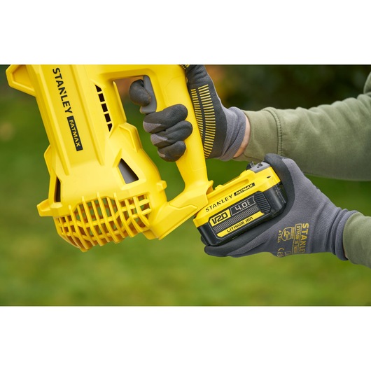 Photo of STANLEY SFMCBL714M1 leaf blower with V20 4.0Ah battery being inserted, close-up outdoor view.