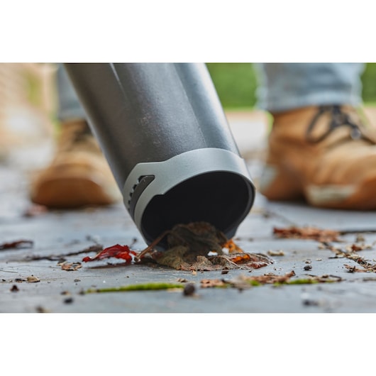 STANLEY SFMCBL7B blower tube close-up clearing leaves and debris on pavement.