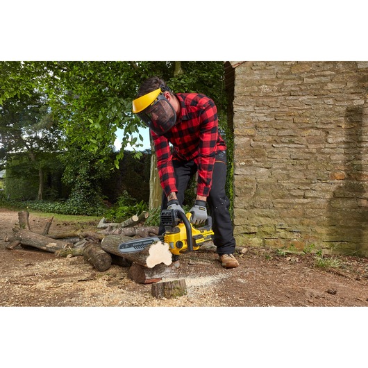 STANLEY SFMCCS630M1 chainsaw in use outdoors, cutting wood, man wearing safety gear.