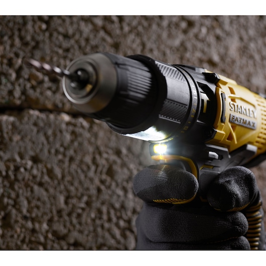 Stanley SFMCD711B cordless drill with LED light, close-up in use, yellow and black body, drill bit attached.
