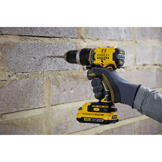 STANLEY SFMCD721B cordless drill in use on masonry wall, close-up side angle.