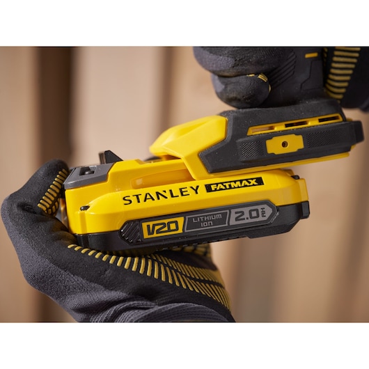 Photo of STANLEY SFMCD750D2K cordless drill with V20 2.0Ah lithium-ion battery in gloved hands.