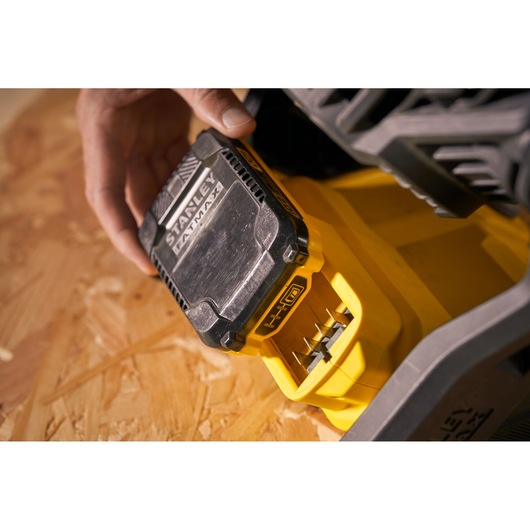 Photo of STANLEY SFMCE001B battery pack being inserted into yellow power tool, close-up view.