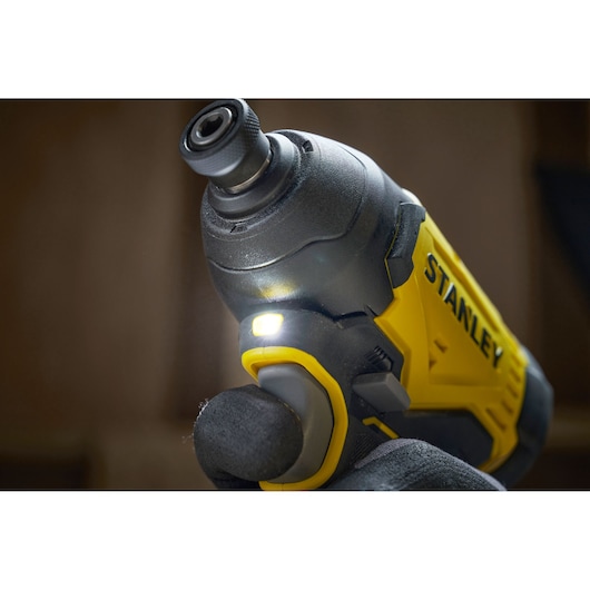 Close-up of a yellow STANLEY cordless impact driver with LED light turned on.