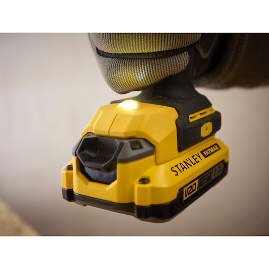 Close-up of STANLEY SFMCF900B cordless impact driver in use, yellow and black design, visible LED light.