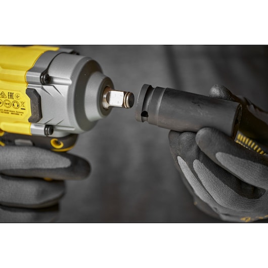 Person in gloves attaching socket to a yellow and grey STANLEY impact wrench.