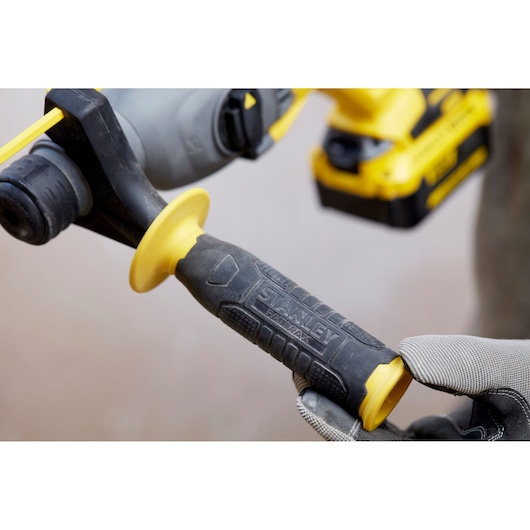Photo of STANLEY SFMCH900M22 drill grip handle, black and yellow ergonomic design, worn by gloved hand.