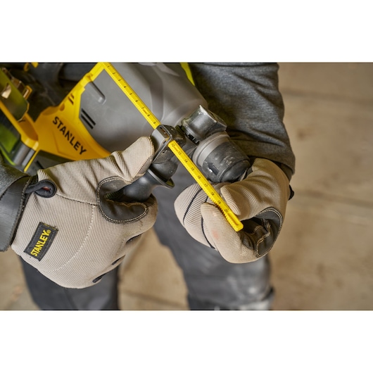 Photo of STANLEY SFMCH910R1T rotary hammer with depth gauge, worker in gloves adjusting tool.