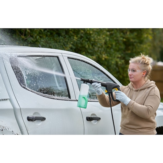 STANLEY SFMCPW1500B pressure washer in use cleaning a white car, side view, outdoors.