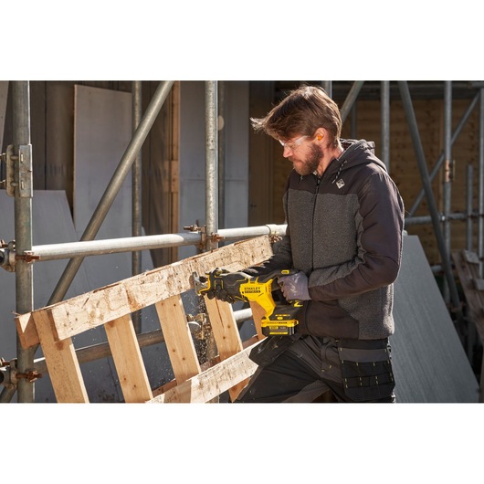 Photo of STANLEY SFMCS311M1T reciprocating saw cutting wood pallet on construction site.