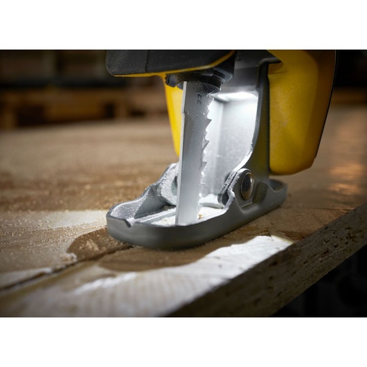 STANLEY SFMCS311M1T jigsaw cutting wood, close-up of blade and base, illuminated by LED light.