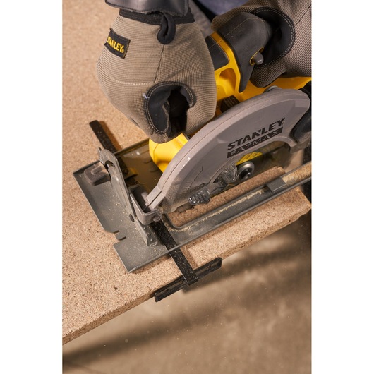 STANLEY SFMCS500M1S circular saw cutting wood, close-up action, yellow and gray tool held by gloved hands.