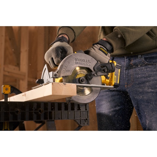 Stanley SFMCS500M1S circular saw cutting timber, close-up, with sawdust flying in workshop.